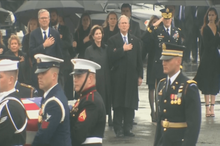 President Bushing standing with his hand over his heart in the rain