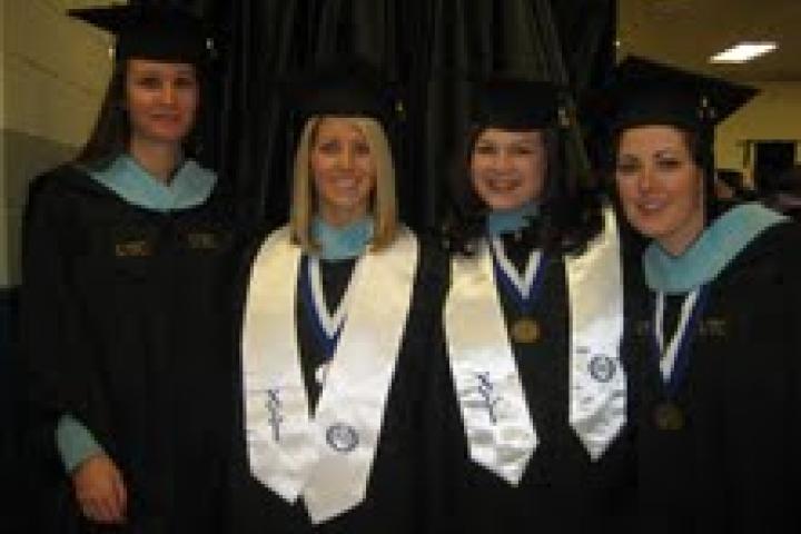 Four students in group photo wearing graduation gowns