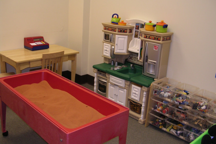 image of play room for play therapy with a child-size desk, sand table, play kitchen