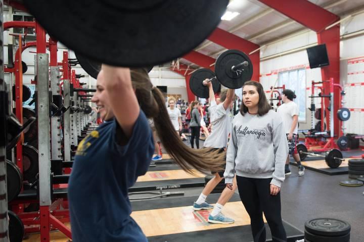 One student lifts a weight while another watches
