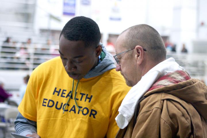 Health Educator in a yellow shirt talks to a man
