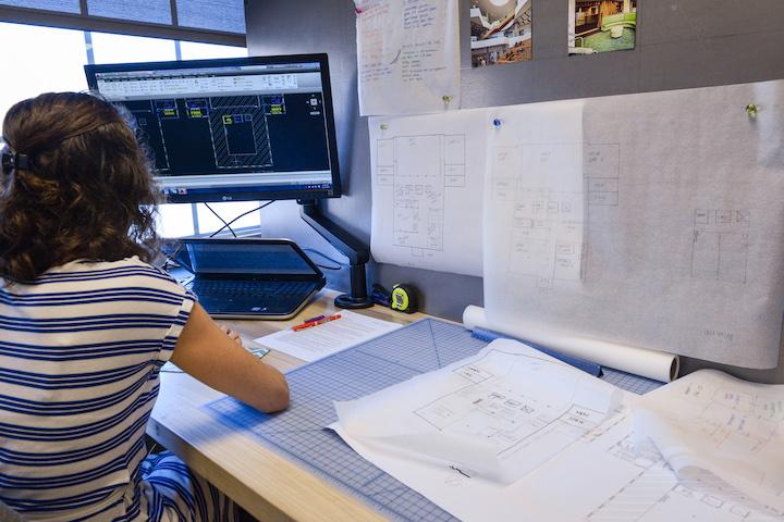 Female student in front of computer and blueprints