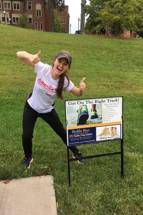 Girl with thumbs up next to sign