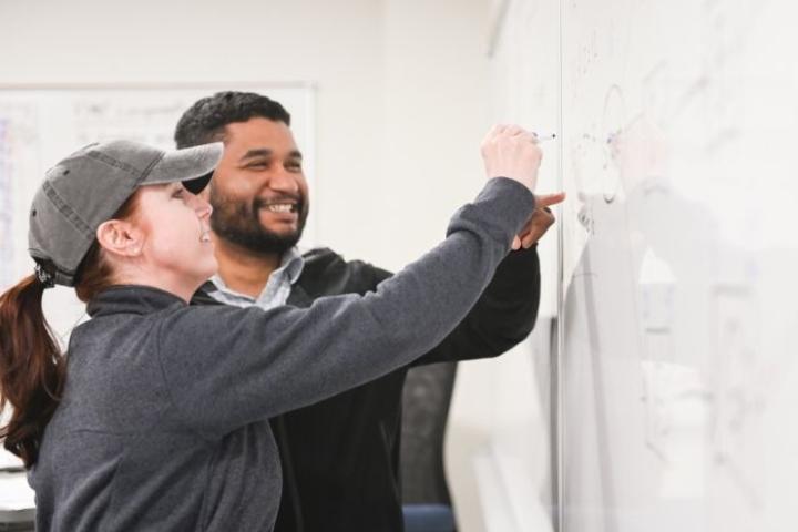 PMP Exam Prep Participants working a critical path formula on a white board