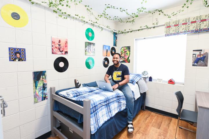 male resident sitting in on-campus bedroom