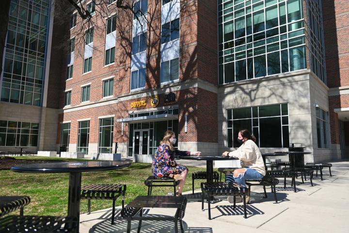 two girls sitting at table outside west campus