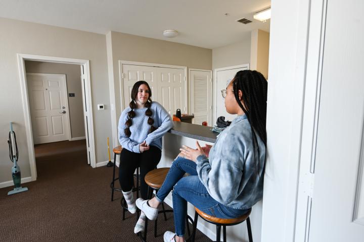 two female sitting on kitchen barstools talking