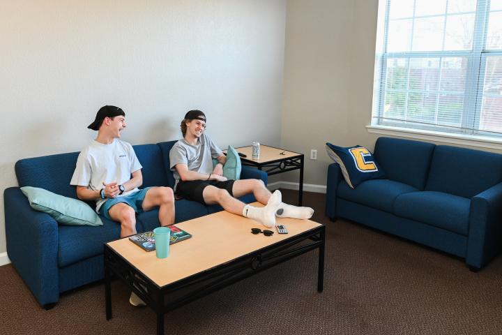 two guys watching tv in living room of walker apartments