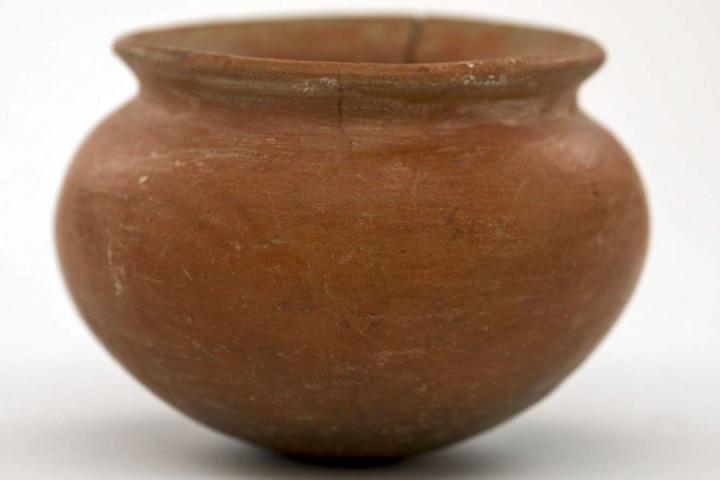 Pre-Columbian ceramic vessel made from a red clay. Vessel has a wide body and a flared rim.