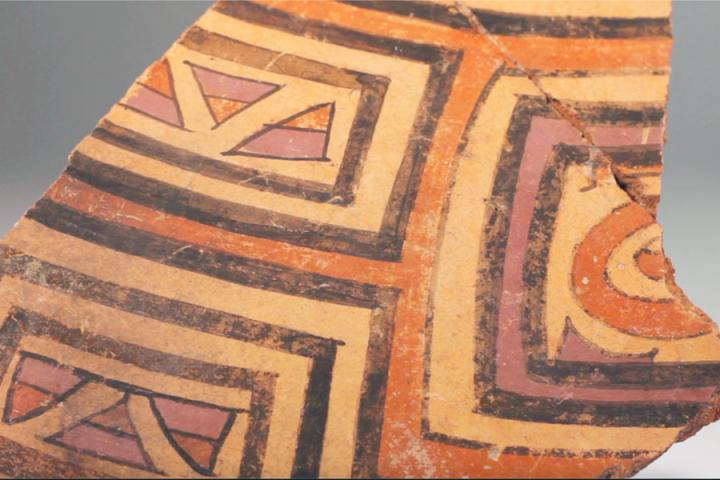 Pre-Columbian ceramic sherd with decorative lines in black, purple, and red slip.