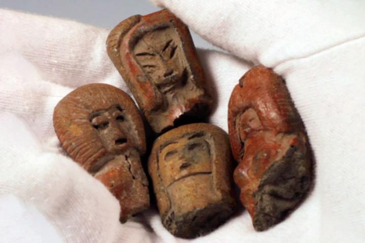 Pre-Columbian ceramic figurine heads made from red clay.