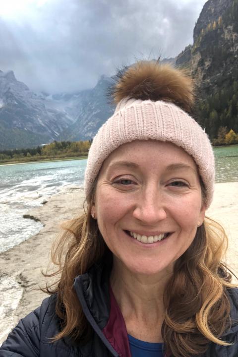 portrait of Jennifer Boyd, posing near a river with mountains in the background