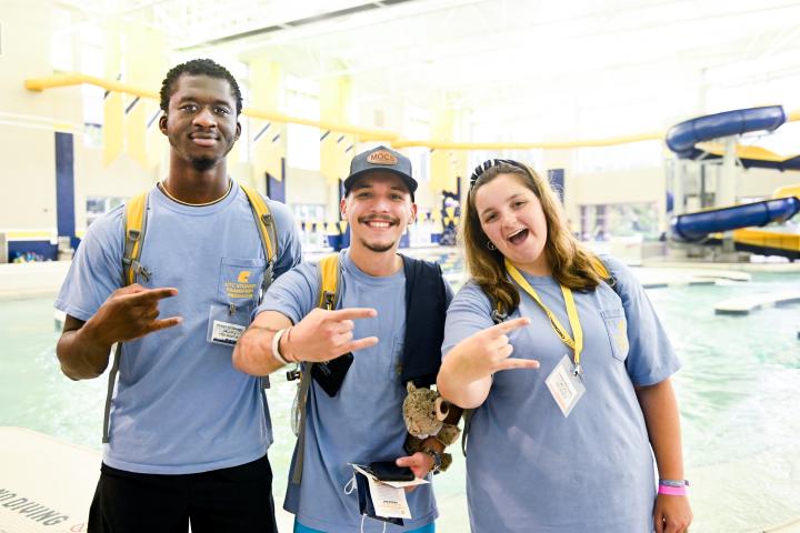 Three students standing in front of pool