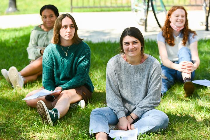 Humanities students outside in grass listening to teacher