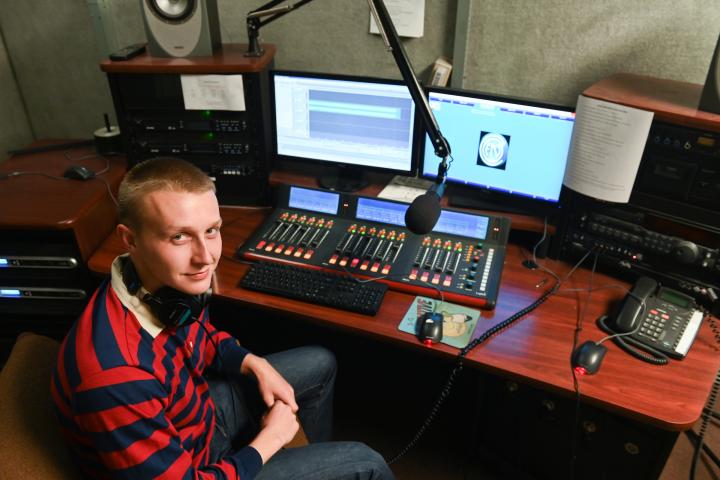 Perch radio manager Student sits in front of Perch radio equipment
