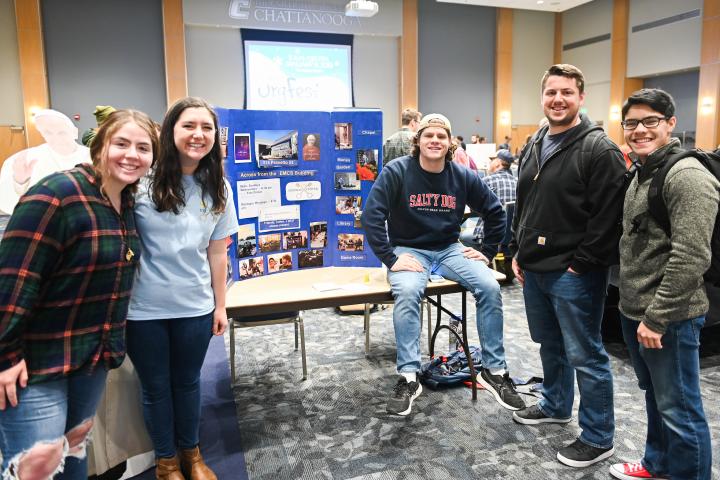 Student pose around and organization table at the winter organization fair. 