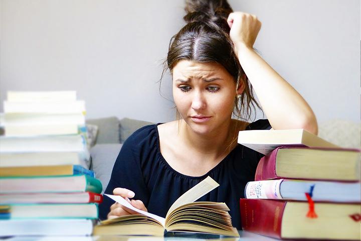 Student surrounded by an abundance of books with a stressed appearance