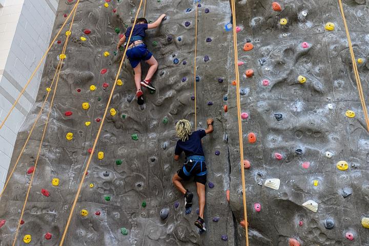Two campers climb at the climbing tower in the ARC.