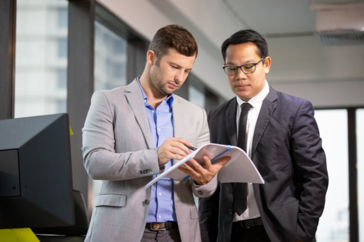 two male businessman looking at white paper