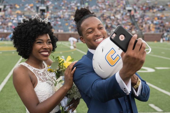 Homecoming King and Queen take a selfie with a smartphone.