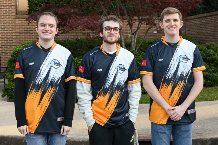 Three of the UTC League of Legends A team players pose in their jerseys.