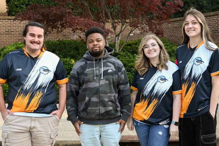 Four of the UTC League of Legends B team players pose in their jerseys.