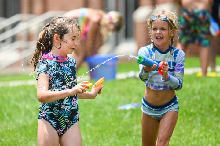 Two children play outside the ARC with water guns and water balloons at Mocs Adventure Camp.