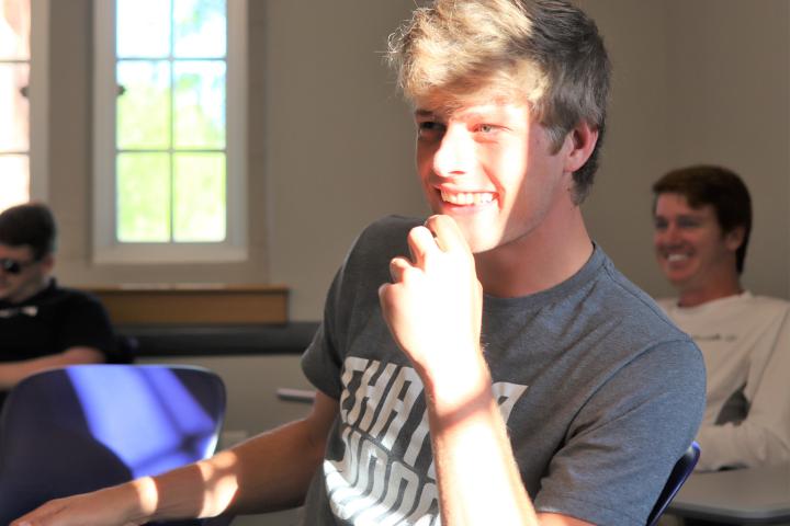 College student in gray t-shirt laughs during a sales class at the UTC Gary W. Rollins College of Business.
