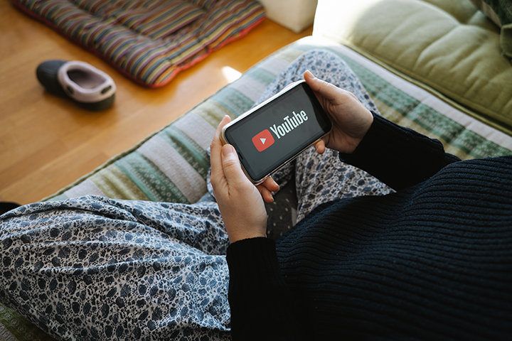Photo of a person wearing pajamas watching YouTube on their phone.