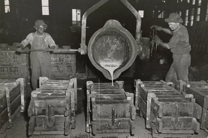 Two men are pouring molten metal into molds at Wheland Foundry in 1950.