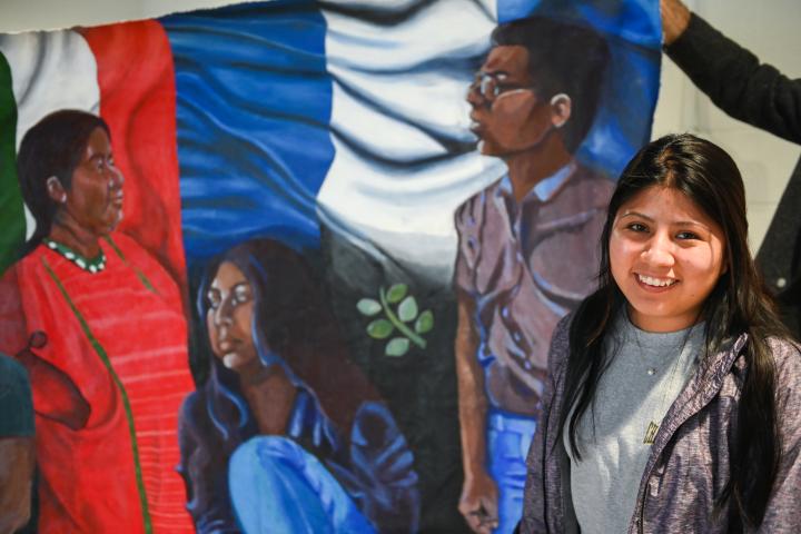 student in front of a mural