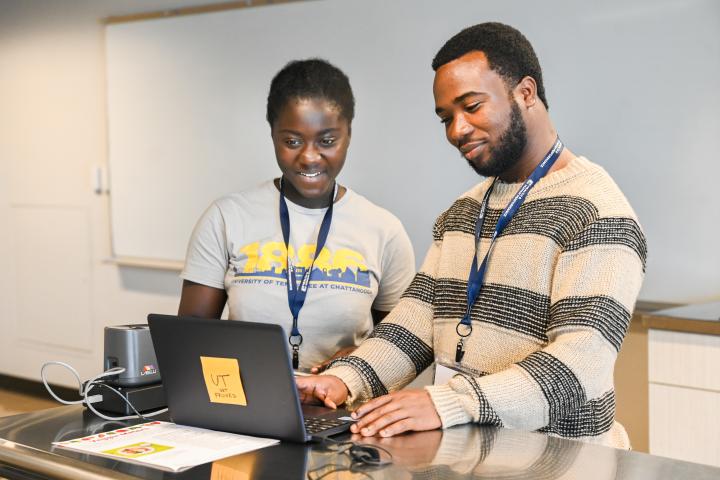 Two students using a laptop in class