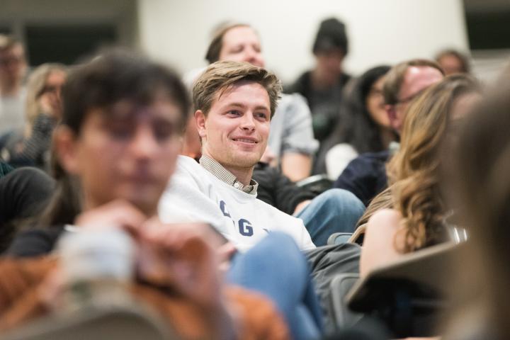 Students sitting in a crowd with the focus on a male student