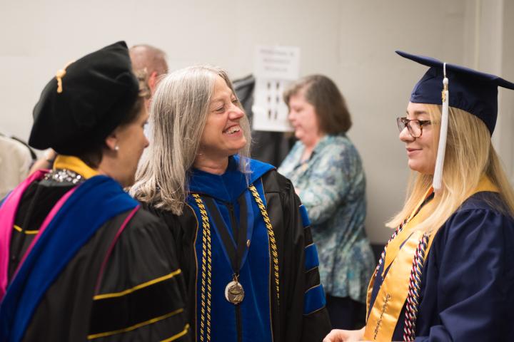 Gathering after the Honors Commencement with the Dean, Dr. Linda Frost, a student and one other person.