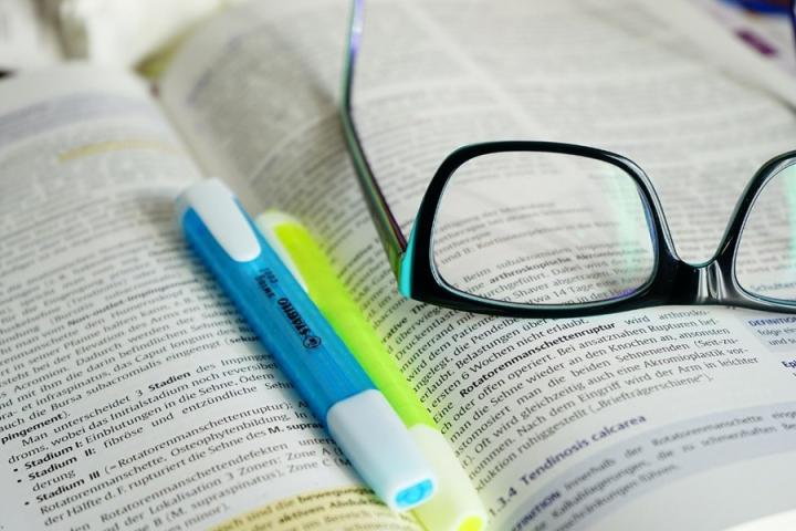 Photograph of glasses and a two highlighters resting on a printed article