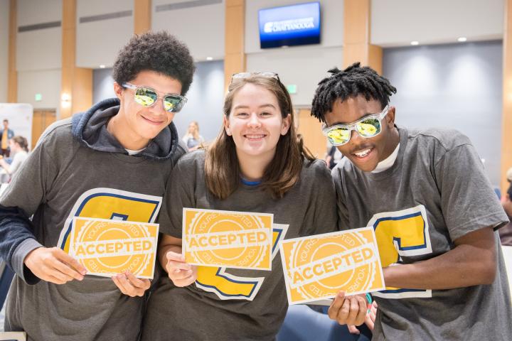 Three students holding accepted letters 