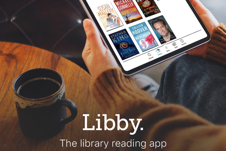 Photograph of a tablet open to the Libby app while the user enjoys a cup of coffee.