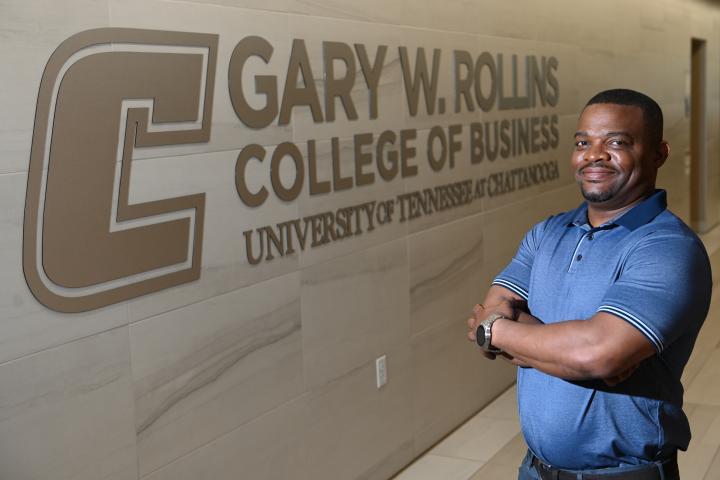 Student standing in front of Gary W. Rollins College of Business sign