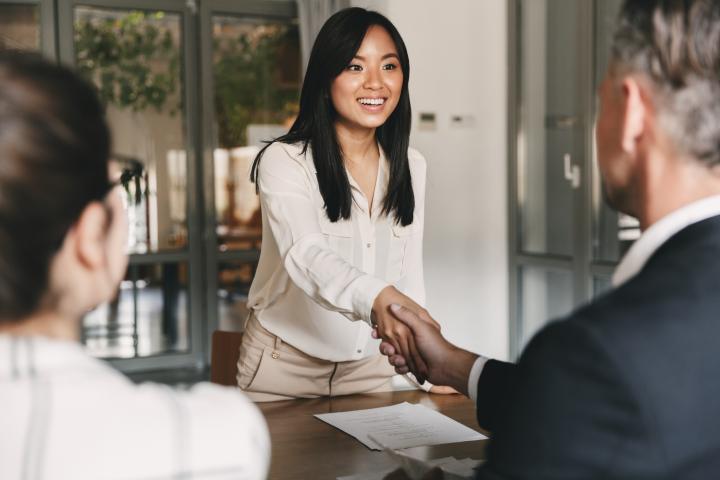 Woman wearing white shaking hands with a man in suit