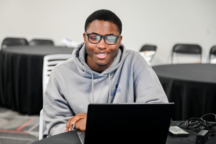 Student wearing grey hoodie and glasses at internship working. 