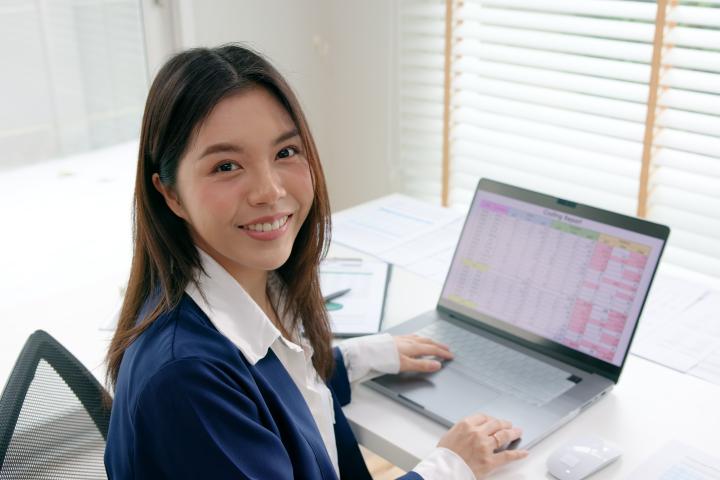 Student smiling with spreadsheet open on laptop