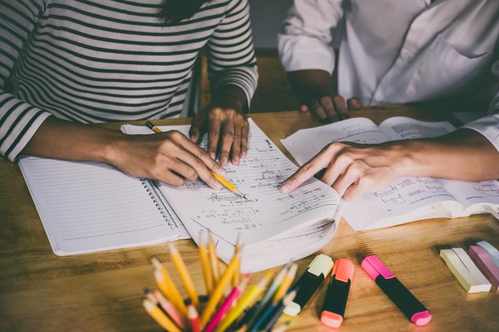 Students hands with papers and pencils around them