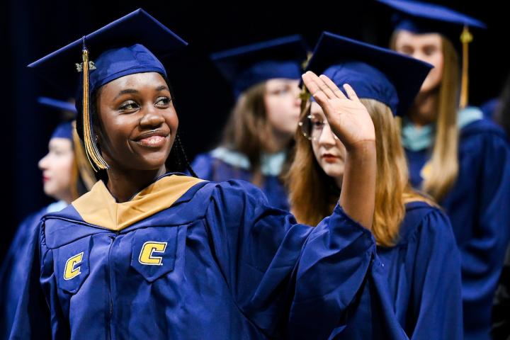 Student waving while at her graduation ceremony