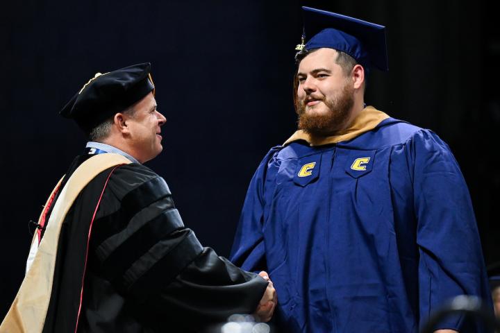 Masters student graduating college shaking hands with dean