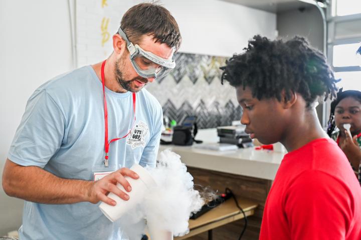 Student watching a teacher perform an experiment