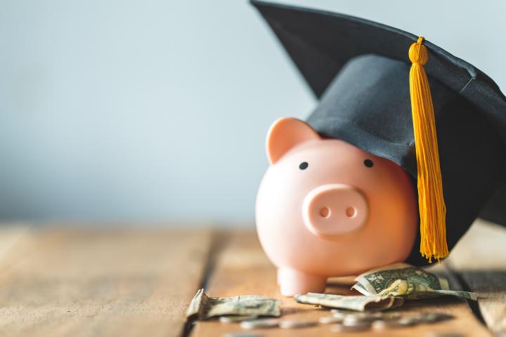 A piggy bank with grad hat and money surrounding it