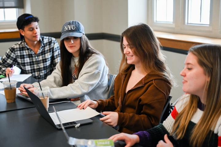 Students with laptops as they smile working on assignment