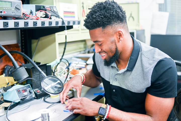 Student working in an electrical engineering lab soldering a project