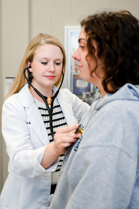 Female nurse checking the heart rate of a female student.