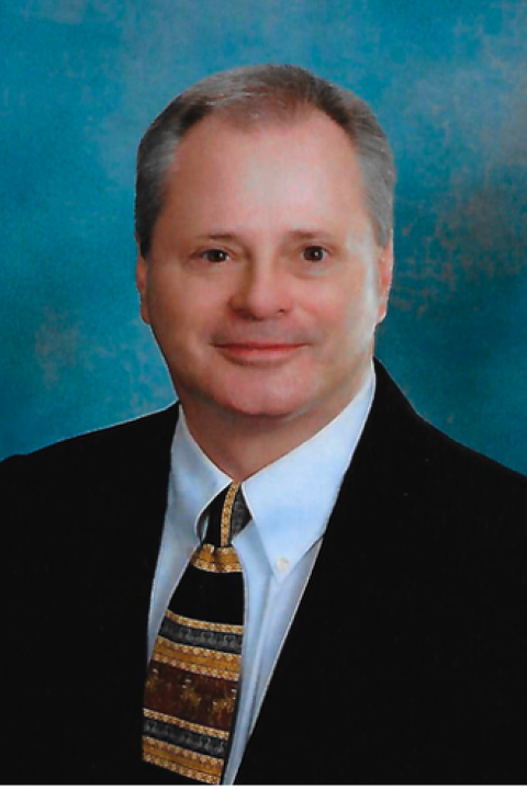 Headshot of Andy Walker in a dark suit, light blue shirt, and patterned tie.